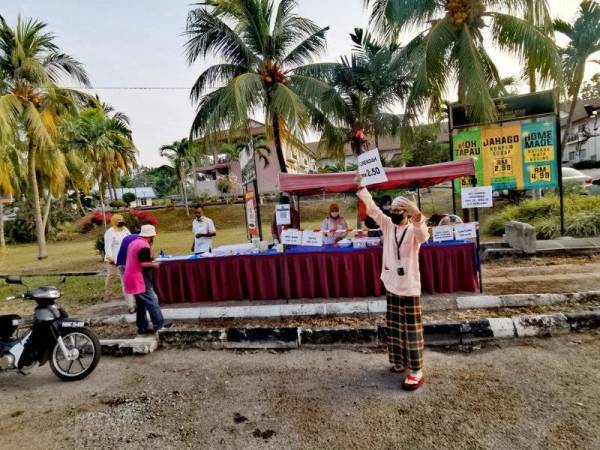 Shaharim memegang plakad bagi menarik orang ramai membeli makanan yang dihasilkan pihak hotel dan dijual di gerai tepi jalan di luar Hotel Seri Malaysia, Port Dickson pada Rabu.