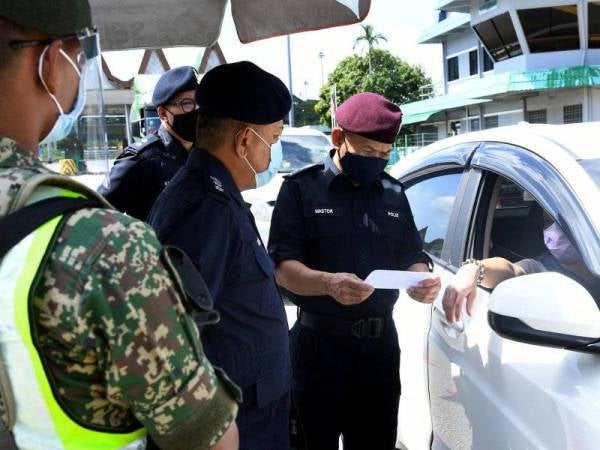 Mastor (kanan) memeriksa dokumen pemandu kenderaan di Sekatan Jalan Raya (SJR) di Plaza Tol Port Dickson, hari ini. Foto Bernama