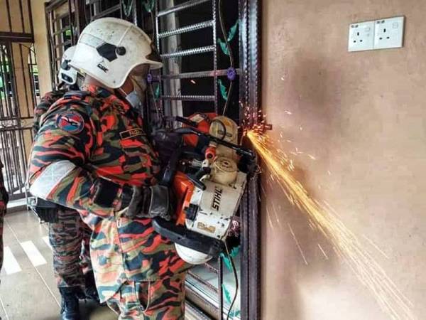 Anggota bomba dari BBP Bukit Angin memotong mangga di pintu rumah terbabit pada Khamis. -Foto Friends of Bomba Bukit Angin Temerloh