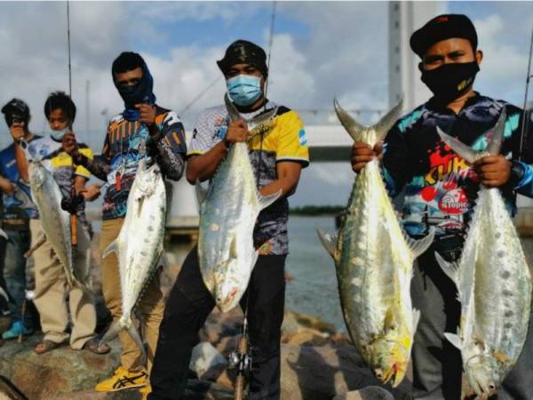 Sebahagian pemancing menunjukkan ikan talang yang dinaikkan hasil aktiviti memancing di kawasan berhampiran jambatan angkat di Kuala Terengganu pada Jumaat.