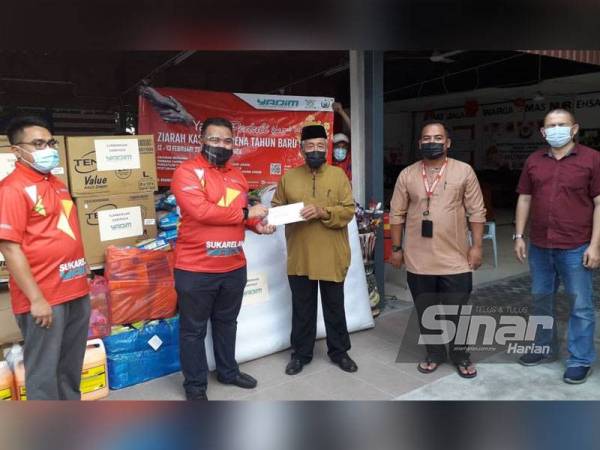 Tuan Kamarul Arief (kiri) memberi sumbangan barang keperluan asas dan wang tunai kepada Md Sharipin di Pusat Jagaan Warga Emas Nur Ehsan, Kempas, Johor Bahru pada Jumaat.