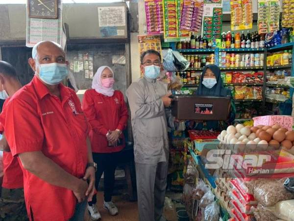 Mohamed Farid (dua dari kanan) menyampaikan bantuan kepada peniaga di Pasar Kubang Pasu pada Sabtu.