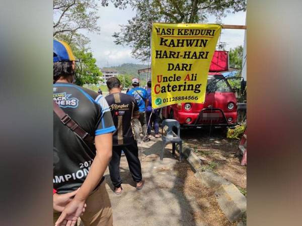 Orang ramai beratur bagi mendapatkan menu nasi kenduri kahwin.