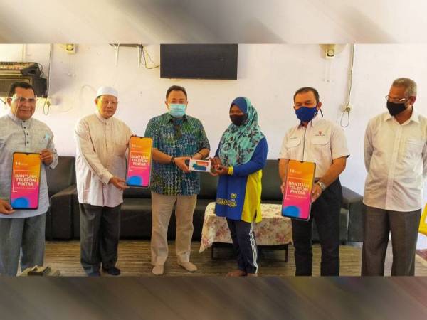 Sheikh Fadzil (dua dari kiri) menyerahkan telefon pintar kepada masyarakat orang asli suku Kensi di Kampung Lubuk Legong, Baling pada Ahad.