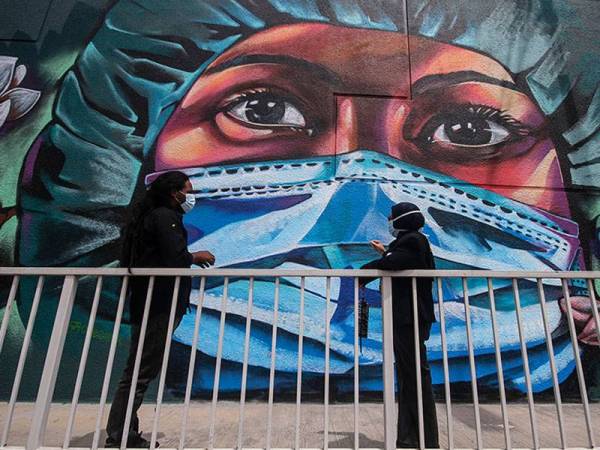 Iskandar 41 (kiri) bersama Rahani (kanan) melihat lukisan mural  “Kita Jaga Kita” yang kini menjadi slogan masyarakat Malaysia dalam memerangi Covid-19. Foto Bernama