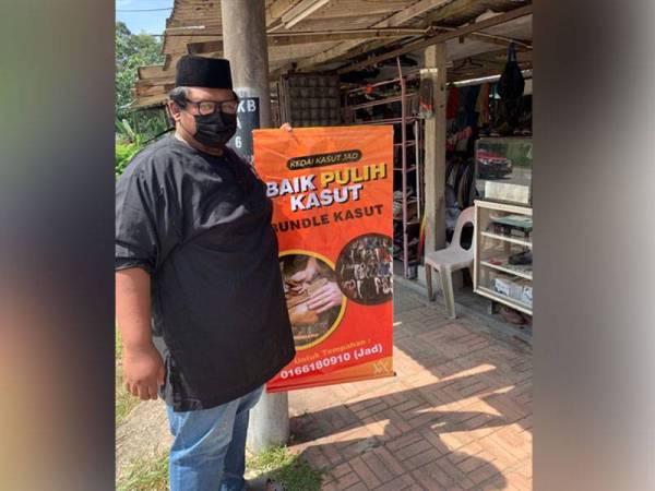 Megat Muhammad Faris menunjukkan bahan iklan yang diberikan secara percuma kepada peniaga kecil di sekitar Kampung Si Rusa, Port Dickson pada Ahad.