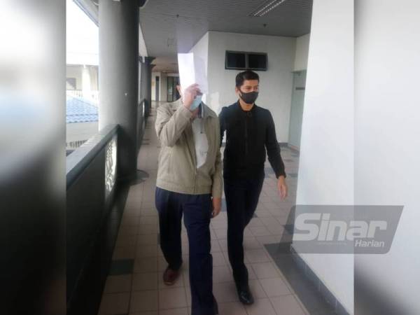 Abd.Rahim (kiri) menutup muka selepas mengaku bersalah di Mahkamah Sesyen di sini, pada Rabu kerana menerima suapan RM4, 000, pada empat tahun lalu.