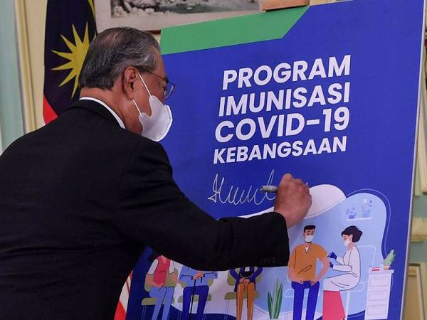 Perdana Menteri Tan Sri Muhyiddin Yassin ketika melancarkan Buku Panduan Program Imunisasi Covid-19 Kebangsaan di Bangunan Perdana Putra hari ini. - Foto Bernama