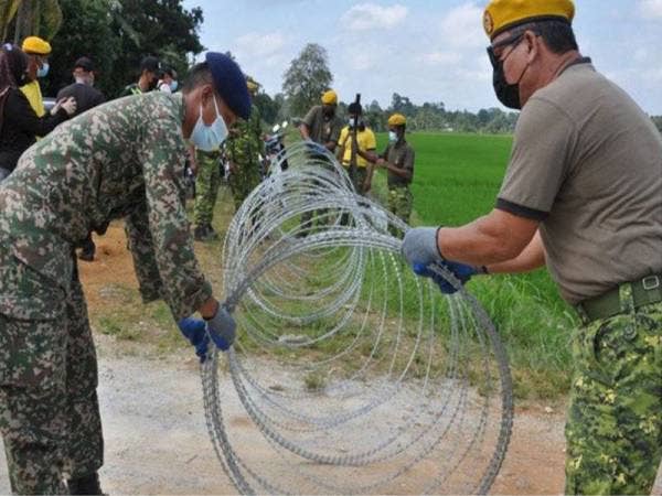 Anggota Angkatan Tentera Malaysia (ATM) dan Jabatan Sukarelawan Malaysia (RELA) memasang gelungan kawat duri untuk diletakkan pada salah satu laluan tikus di sekitar kawasan PKPD yang dikenakan di sebuah kawasan di Besut. Foto Bernama 