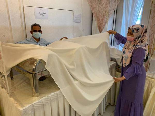 Noor Laila (kanan) menutup bekas makanan yang disediakan di dewannya di Tunjong disini.