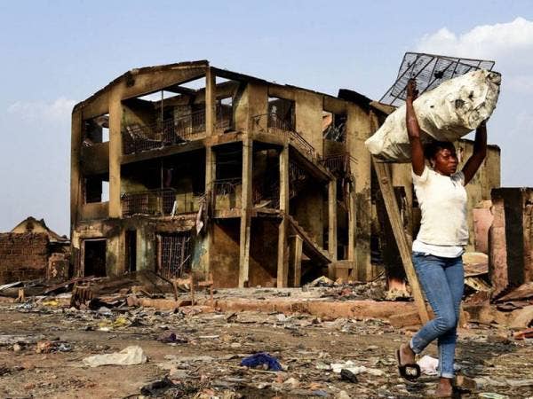 Gambar fail menunjukkan seorang wanita berjalan dekat bangunan tiga tingkat yang musnah terbakar selepas pergaduhan etnik berlaku di Pasar Shasha selatan Nigeria pada minggu lalu. - Foto AFP