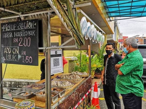 Mansor (kiri) menunjukkan kiosk yang menjual nasi lemak pandan dan bunga telang secara pandu lalu kepada Nazri pada Selasa.