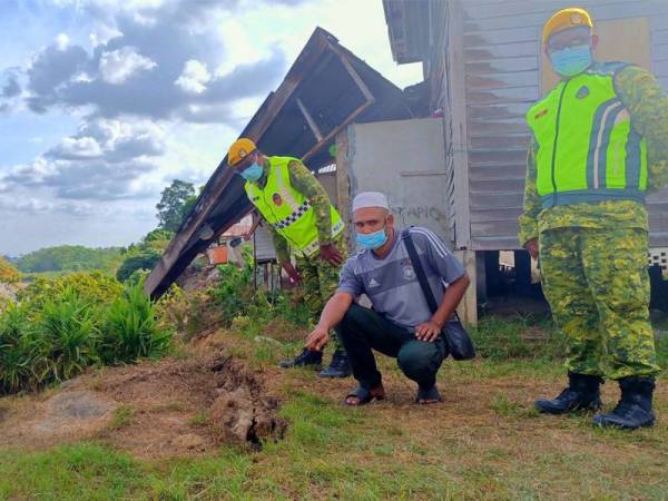 Mohammad Azmi (tengah) bersama anggota Jabatan Sukarelawan Rakyat (Rela) menunjukkan keretakan yang berlaku susulan runtuhan tebing Sungai Kelantan yang berlaku di Kampung Pohon Chelagi, Pasir Mas.