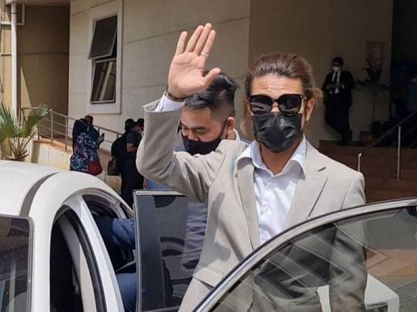 Syed Shah Iqmal melambai kepada petugas media di Mahkamah Majistret Petaling Jaya selepas prosiding kes jenayah yang dikenakan terhadapnya hari ini.