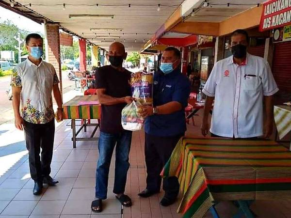 Mohd Kholib Hamid (kanan) memerhatikan Zaidi (dua dari kanan) Mahmud menyerahkan sumbangan barangan keperluan asas kepada peniaga terjejas di Kota Setar.