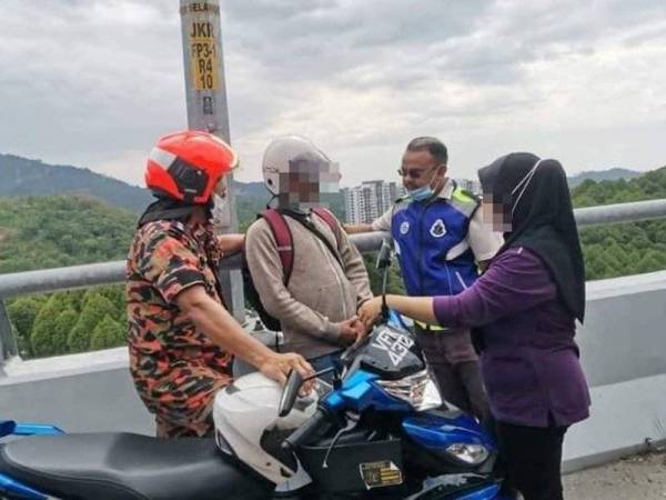 Lelaki tersebut ditenangkan oleh anggota polis, bomba dan bekas isterinya di lokasi kejadian. Foto: Gambar tular.
