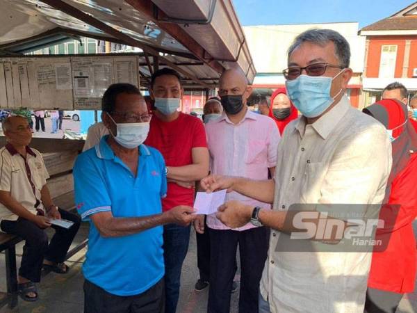 Mohamed Farid (kanan) menyampaikan sumbangan baucar minyak kereta di stesen kereta sewa di Kota Bharu, Pasar Pohon Pinang, Kota Bharu pada Sabtu.