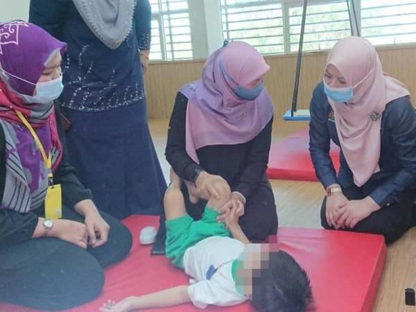 Rina (kanan) menyantuni seorang kanak-kanak Taska OKU Ikhlas di Yayasan Toh Puan Zurina, Pantai Peringkat di Melaka pada Sabtu.