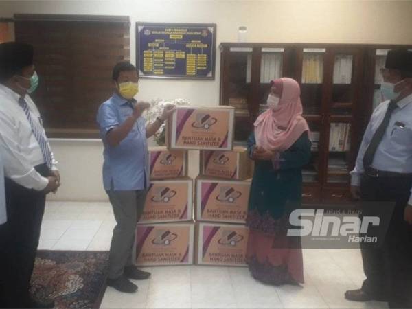 Mohd Nizar (dua dari kiri) turun ke SMK Agama Kedah, Alor Setar dan menyerahkan pelitup muka dan cecair pembasmi kuman kepada Rashidah pada Ahad.