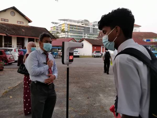 Calon SPM di SMK Anderson, Ipoh mengikuti prosedur operasi standard (SOP) dengan mengimbas suhu sebelum memasuki dewan peperiksaan pada Isnin.