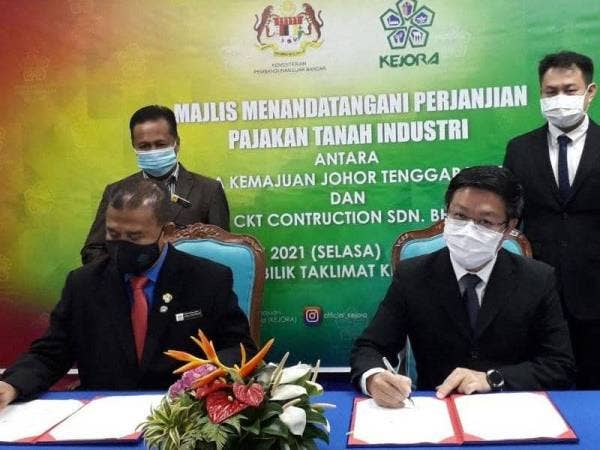Cha Zakaria (kiri) dan Richard Ong menandatangani dokumen dalam Majlis MoU Pajakan Tanah Industri Antara Kejora dan CKT Construction Sdn Bhd di Kota Tinggi pada Selasa.