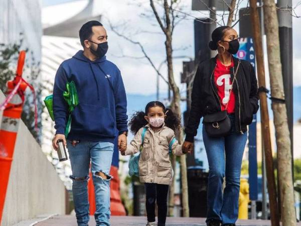Gambar menunjukkan dua orang dewasa dan seorang kanak-kanak memakai pelitup muka ketika berjalan di Los Angeles. - Foto: AFP
