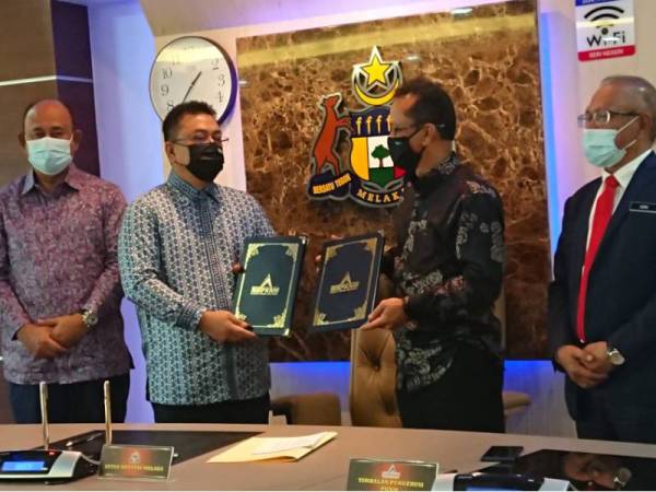 Sulaiman (dua dari kiri) bertukar perjanjian dengan PKNM di Seri Negeri, Ayer Keroh, Melaka pada Khamis.