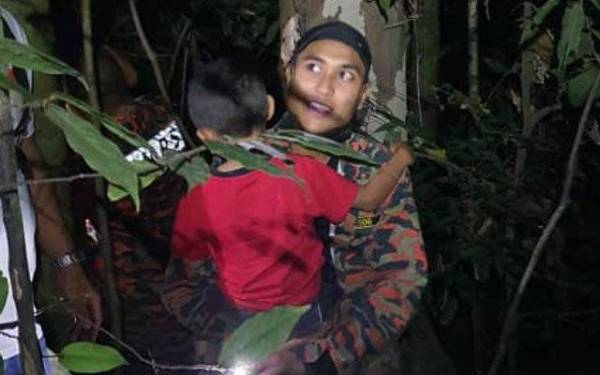 Seorang anggota bomba membawa kanka-kanak yang sesat untuk keluar dari kawasan bukit di Kampung Tandop, Baling pada Khamis.