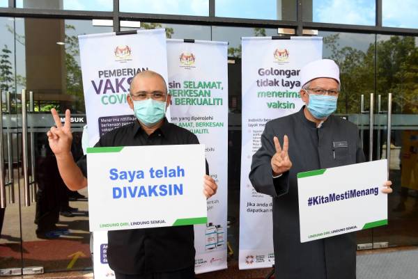Dr Zulkifli (kanan) bersama Ronald Kiandee bergambar bersama plakad selepas menerima suntikan vaksin Covid-19 jenis Pfizer BioNTech di Pejabat Kesihatan Daerah Putrajaya Presint 11 hari ini. -Foto Bernama