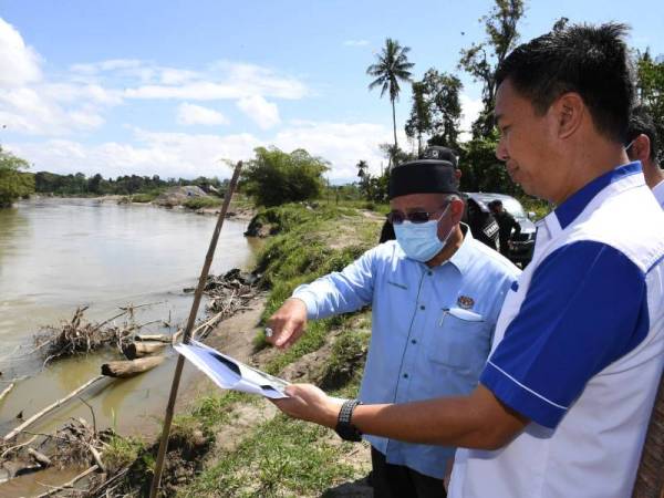 Tuan Ibrahim (kiri) diberi penerangan oleh Jurutera Jabatan Parit dan Saliran Kota Belud, Jaffri Bahan (kanan) mengenai kawasan tambatan banjir yang akan dibina di Sungai Tempasuk ketika melakukan lawatan di kawasan banjir dan projek tebatan banjir pada Sabtu. - Foto Bernama