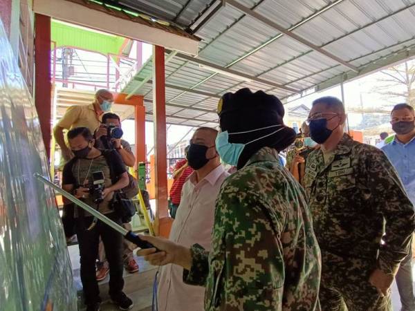 Saarani bersama Mohd Azmurin melihat pelan kerja baik pulih Surau Islahiyah di pekan Lenggong sempena lawatan kerja Projek Jiwa Murni pada Sabtu.