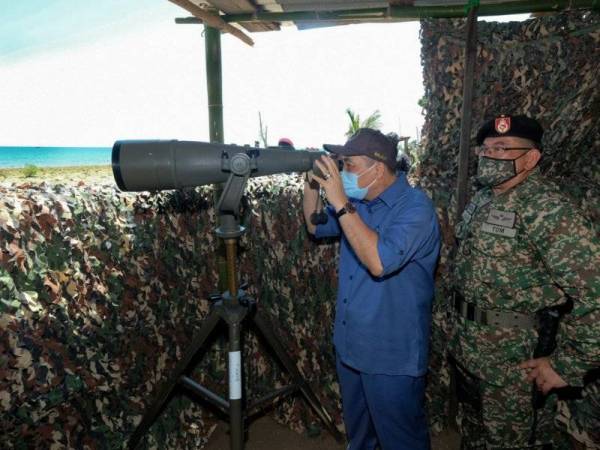 Hajiji (kiri) mencuba teropong pemantau ketika mengadakan lawatan di Pos Kawalan Angkatan Tentera Malaysia (ATM) Tanjung Labian pada Ahad. - fotoBERNAMA (2021) HAK CIPTA TERPELIHARA