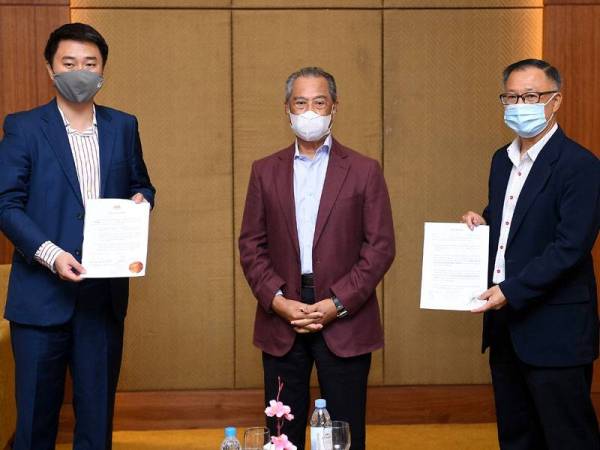 Muhyiddin (tengah) menerima Akuan Bersumpah (SD) daripada Larry Sng Wei Shien (kiri) dan Steven Choong Shiau Yoon. -Foto Bernama