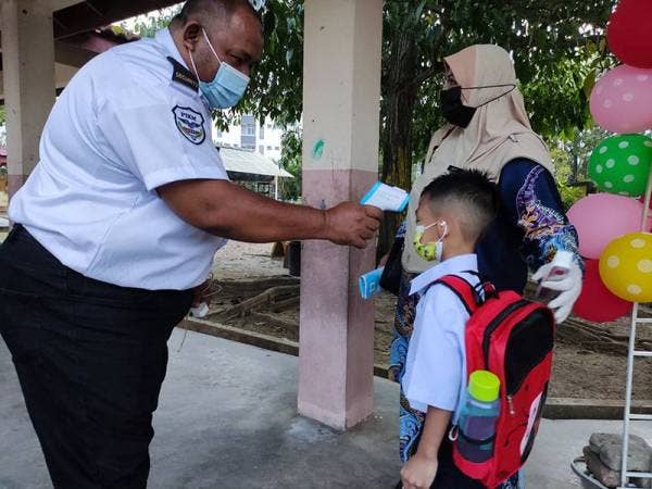 Murid yang hadir ke sekolah diambil suhu badan sebelum mereka masuk ke kelas.