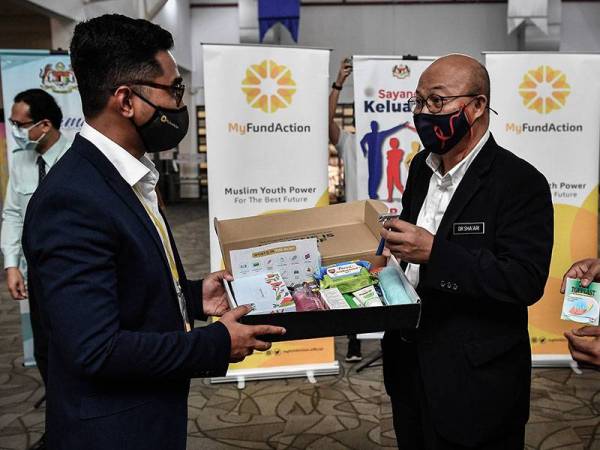 Pengarah Kesihatan Negeri Selangor Datuk Dr Sha'ari Ngadiman (kanan) menerima 'hygiene kit' daripada Ketua Pegawai Eksekuif MyFundAction Muhammad Afiq Mohamad Nazari (kiri) sebagai simbolik penyerahan pada Program Emergency Relief 3.0 di Pusat Kuarantin dan Rawatan Risiko Rendah Covid-19 (PKRC 2.0) MAEPS hari ini. 