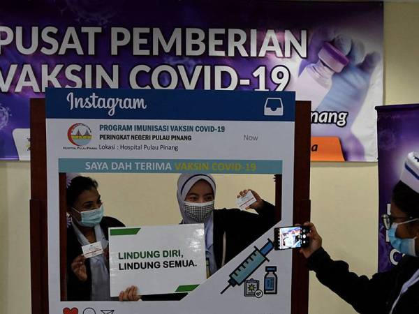 Jururawat Hospital Pulau Pinang (HPP), A.Caroline merakam gambar kenangan rakan setugas D.Amurtha (kiri) dan Aina Munirah Abu Hassan (dua, kiri) selepas mereka mendapat suntikan Vaksin Covid-19 di Pusat Pemberian Vaksin Covid-19 , HPP hari ini.