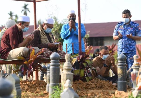 Mohammad Zaini (kiri) di pusara Mohd Afiq Ikmal di Tanah Perkuburan Islam Masjid Al-Barakah Tikam Batu Kedah.