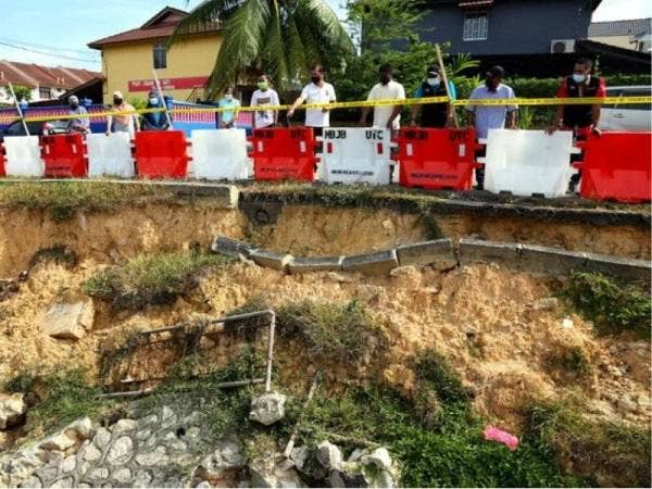 Syed Othman (dua, kanan) dan penduduk setempat menunjukkan keadaan tebing runtuh yang berlaku di Jalan Ketapang 9, Taman Rinting Pasir Gudang hari ini. - Foto Bernama