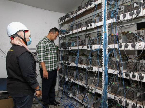 Aibee(kanan) melihat mesin yang digunakan untuk kegiatan melombong bitcoin di Medan Perniagaan Kepayang, Seremban, Negeri Sembilan.
