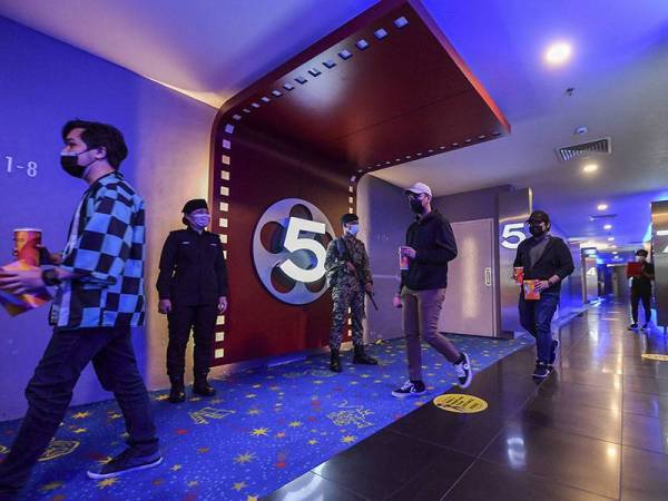 Pegawai Pemantau Pematuhan Prosedur Operasi Standard (SOP), ASP Lenny Kandawar (dua, kiri) bersama Anggota Angkatan Tentera Malaysia (ATM), Azwan Jamil melakukan pemantauan pematuhan SOP pengunjung yang hadir ke panggung wayang Golden Screen Cinema di pusat beli belah Alamanda hari ini.