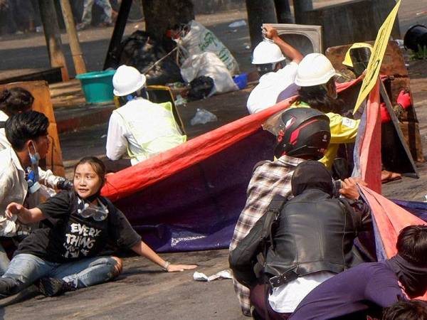 Penunjuk perasaan duduk berlindung di atas jalan raya. Turut kelihatan menyertai protes itu Kyal Sin (kiri). - Foto Reuters