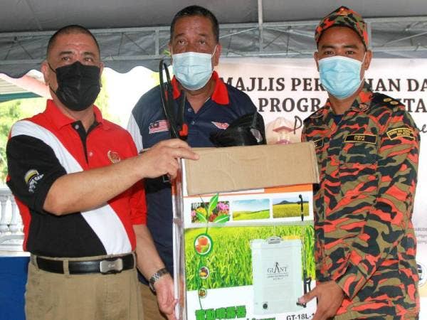 Saarani Mohamad (kiri) menyampaikan barang keperluan untuk melakukan kerja-kerja sanitasi kepada Ketua Balai Balai Bomba dan Penyelamat Lenggong, Farizul Anuar (kanan) pada Majlis Pelancaran Program Sanitasi Covid-19 Peringkat Parlimen Lenggong di Masjid Al Nur Lawin, Lenggong hari ini. - Foto Bernama