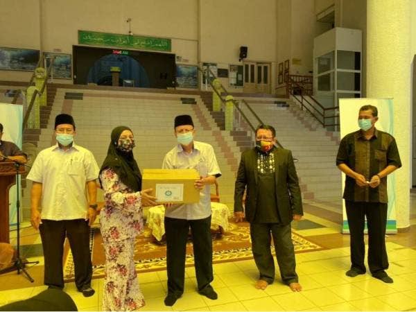 Ahmad Shahir (tengah) menyerahkan sumbangan fidyah berupa pek makanan asasi kepada salah seorang penerima di Masjid As-Salam, Puchong pada Sabtu.