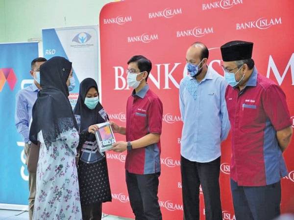 Mohd Muazzam (tengah) menyerahkan tablet kepada Huswatun Hasanah di Dewan Rukun Tetangga, Brickfields baru-baru ini.