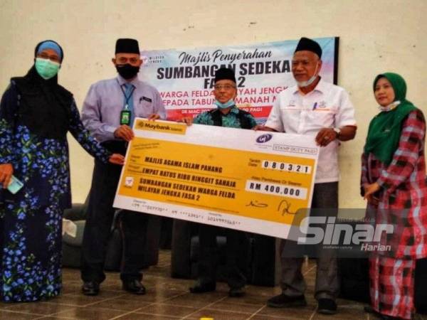 Sulaiman (dua dari kanan) menyerahkan sumbangan untuk fasa kedua kepada Khairuddin (dua dari kiri) pada majlis di Dewan Felda Jengka 16, Jengka pada Isnin.