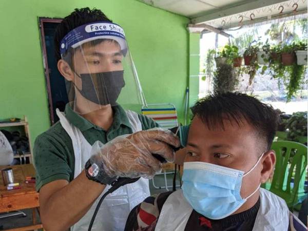 Faris Aidil memangkas rambut salah seorang pelanggannya di kedai gunting yang diusahakan di hadapan rumahnya di Kampung Teluk Bakong, Lambor Kanan, Parit, Perak.