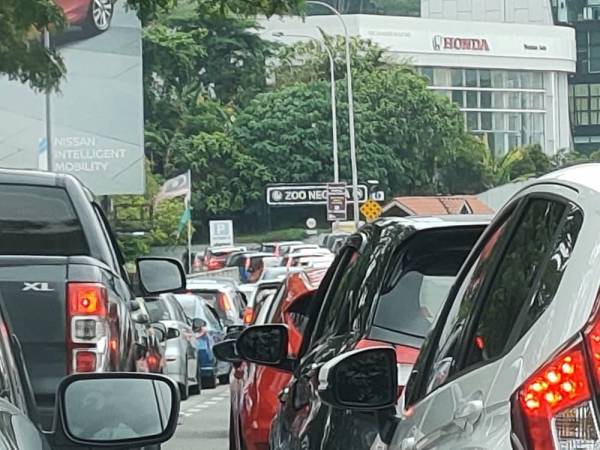 Kereta bersusun menunggu giliran masuk ke kawasan Zoo Negara, Kuala Lumpur pada Ahad.