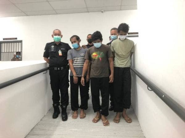 Tertuduh, Mohamad Adam, 26, (kanan), La Muluki, 40, dan La Aliudin, 42, dikawal warden penjara dan polis mahkamah keluar dari Lokap Sementara menuju ke Lokap Mahkamah Kota Bharu selepas selesai didakwa.
