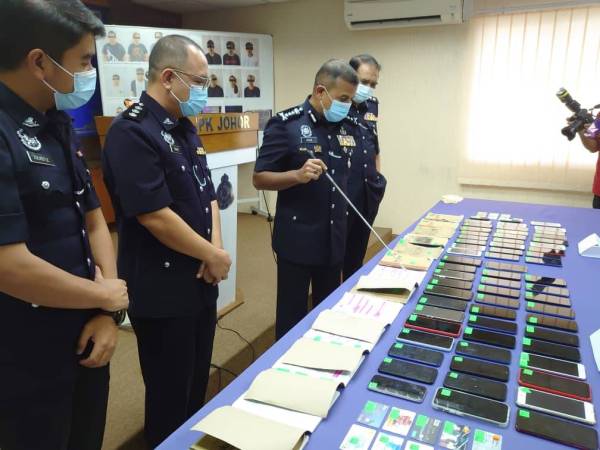 Ayob Khan (tiga dari kiri) menunjukkan barangan rampasan yang digunakan sindiket untuk menipu mangsa dengan menyamar sebagai kenalan pada sidang akhbar di IPK Johor di sini pada Selasa.