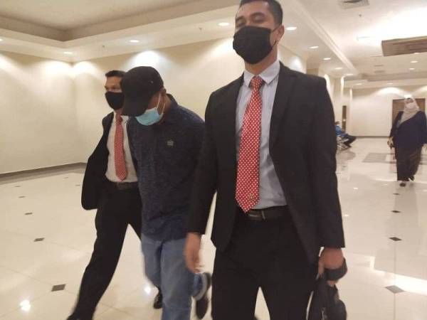 Tertuduh (tengah) dibawa pegawai SPRM keluar dari Mahkamah Sesyen Khas Rasuah, Kuantan selepas selesai sebutan kesnya pada Rabu.